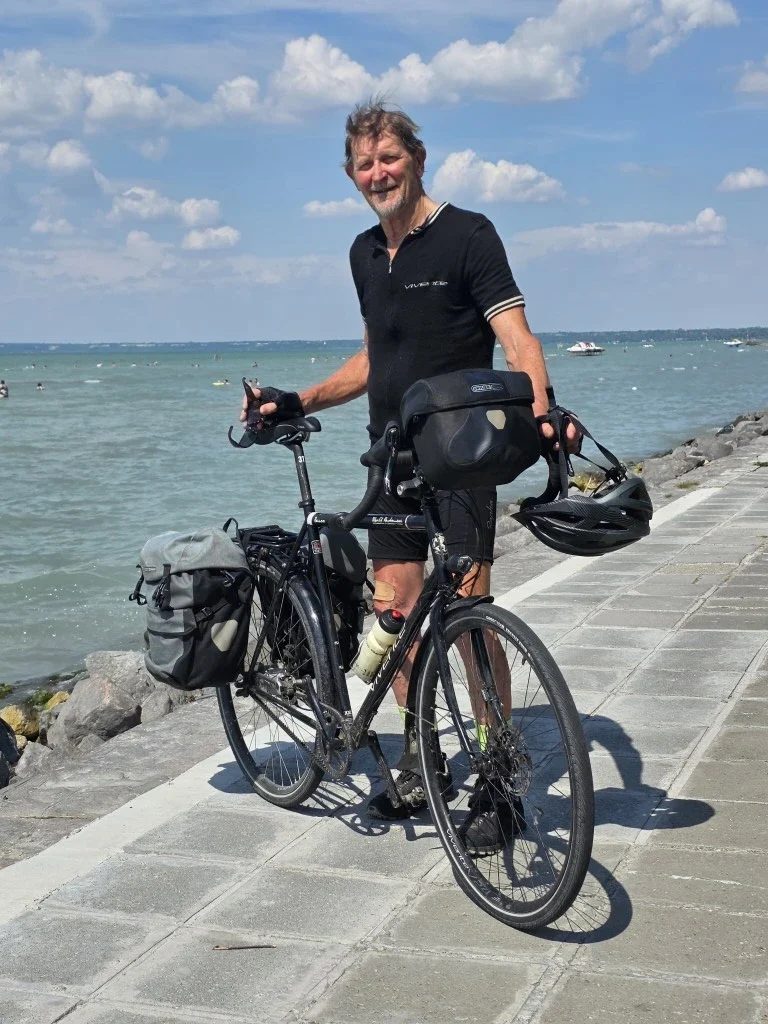 Noel McFarlane standing on a walkway next to the ocean with his Vivente Bike.