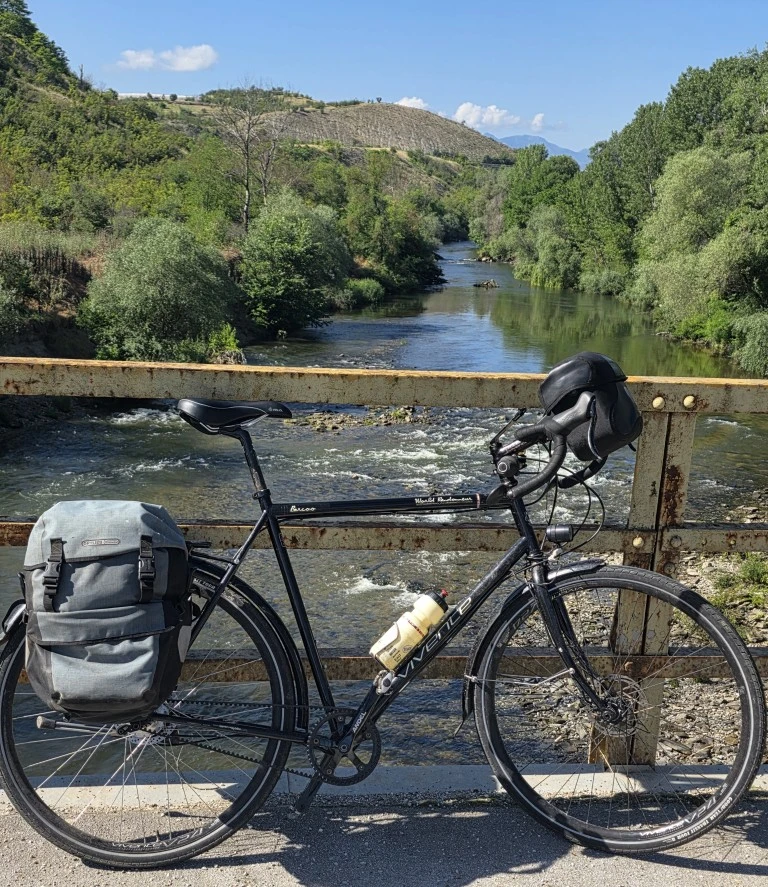 A vivente bike leaning against the railing over a river.