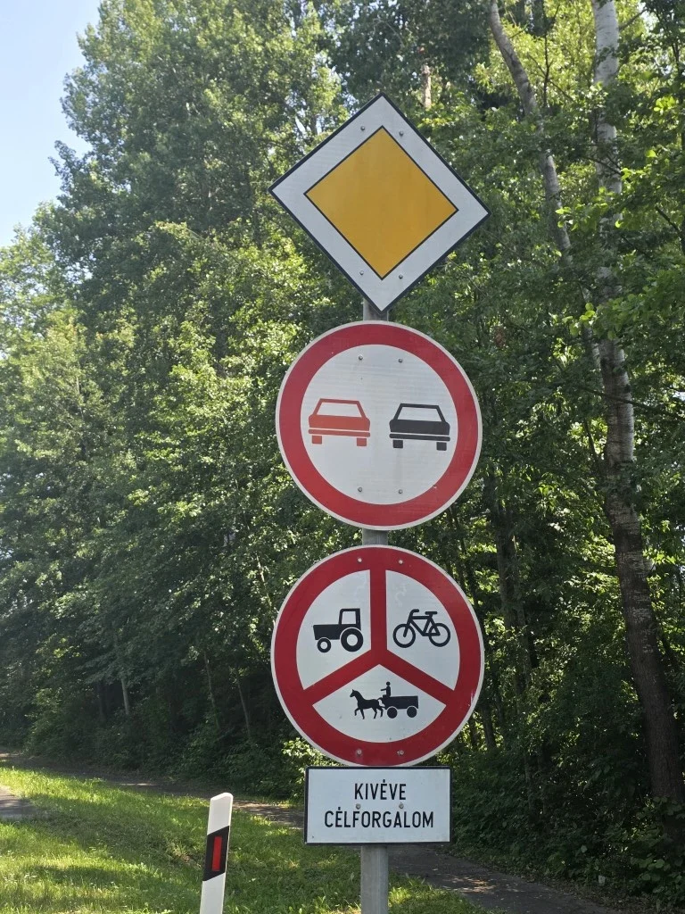 Signage next to the road including a tractor, a bicycle and a horse and cart image.