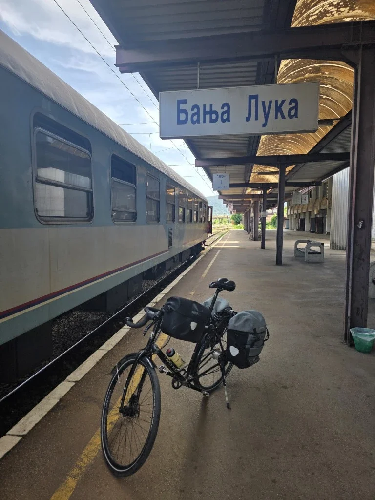 A vivente bike standing up next to a train in a train station in Mostar.